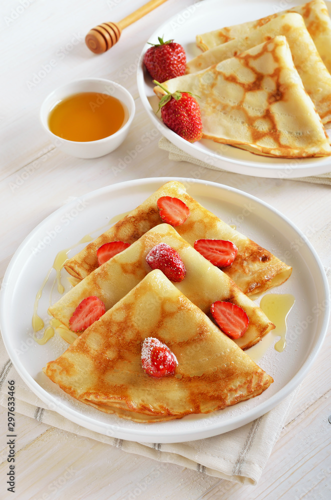 Crepes with strawberry and honey on white plate Crepes with strawberry and honey on white plate
