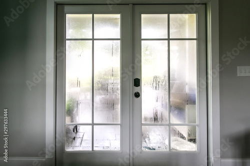The humidity of the outdoor temperature on a summer day in South Georgia. The air conditioning is on inside and the cold air inside makes the back glass pane doors condensate and become foggy. photo