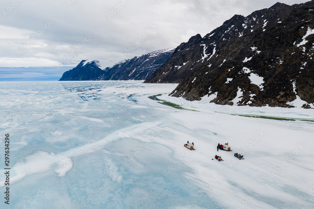 Aerial drone photo of tourists travelling by Qamutiik on the sea ice near Sirmilik National Park in Nunavut, Canada