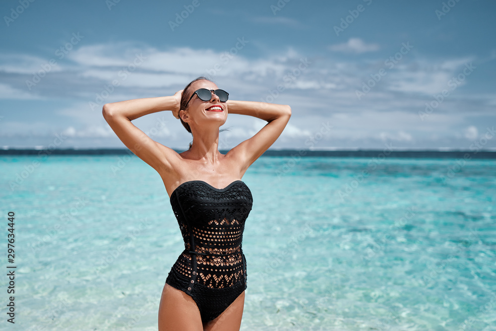 Vacation on the sea. Happy young woman enjoying suntan on the tropical beach.