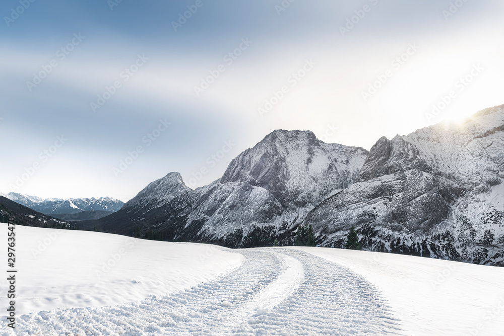 Fototapeta premium Alpine winter landscape with snowy mountains and snowy road