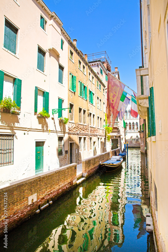 Obraz premium Amazing view to the narrow canal in Venice, Italy. Old buildings reflect in green canal water. 