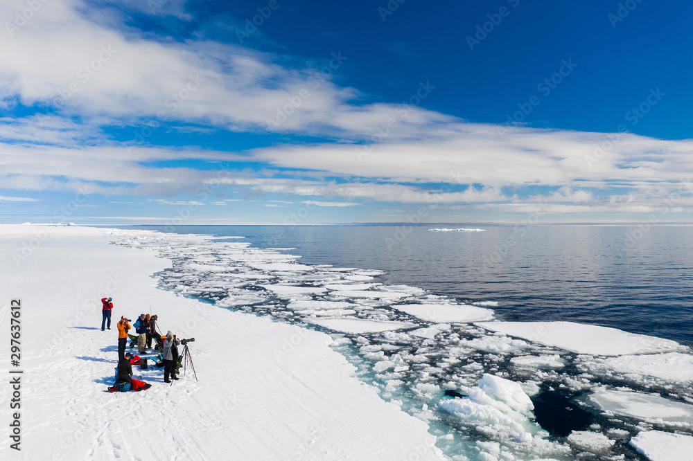 Aerial drone photo of tourists travelling by Qamutiik on the sea ice near Sirmilik National Park in Nunavut, Canada