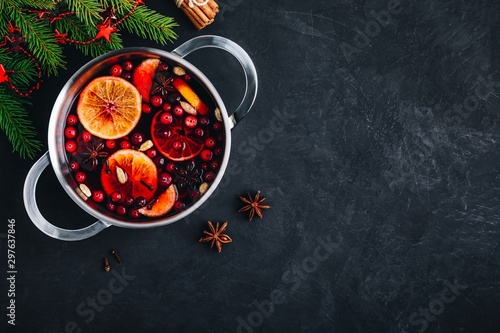 Mulled Wine Hot Drink with Cranberries, oranges, apples and spices on dark concrete background.