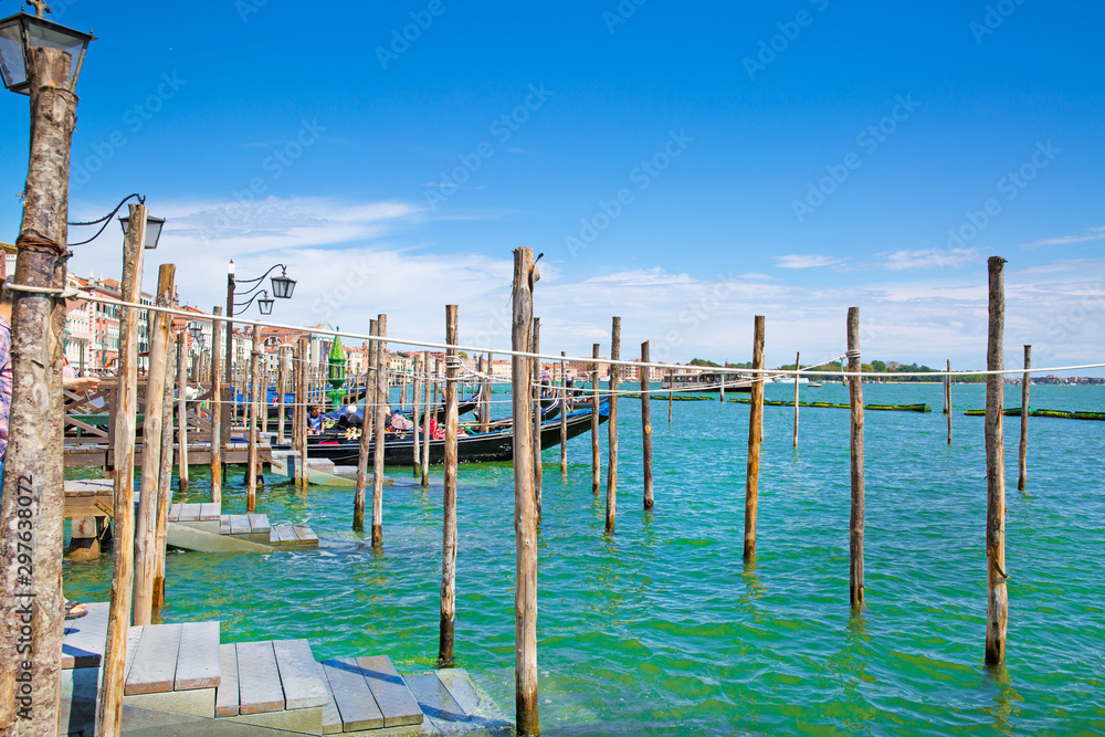 Gondolas and turquoise waters of canal in Venice, Veneto, Italy. Sunny summer day with blues sky. Grand Canal.