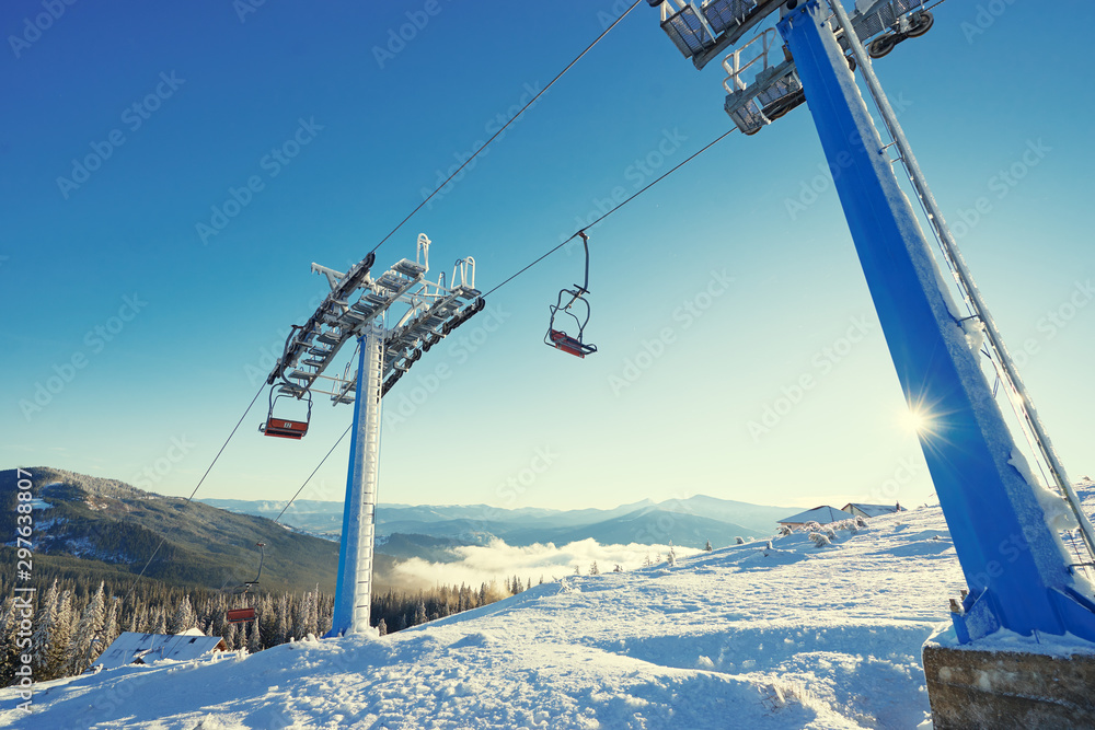 Ski lift with seats going over the mountain and paths from skies and snowboards. Beautiful winter landscape. Ski lift with seats going over the mountain and paths from skies and snowboards. Beautiful winter landscape.