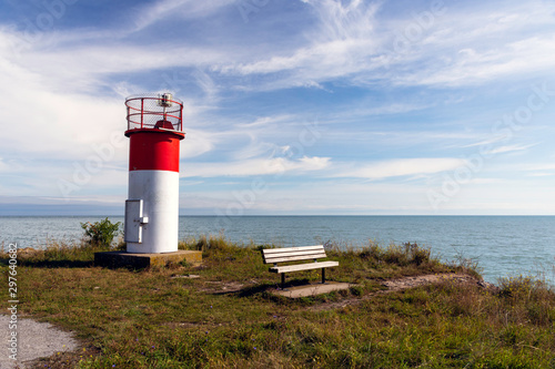 A red and white beacon and memorial bench marks the end of a public walking trail near Niagara on the Lake  Ontario.