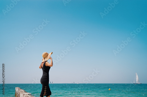 Lonely and calm. Vacation on the sea. Young woman in hat walking on beach.
