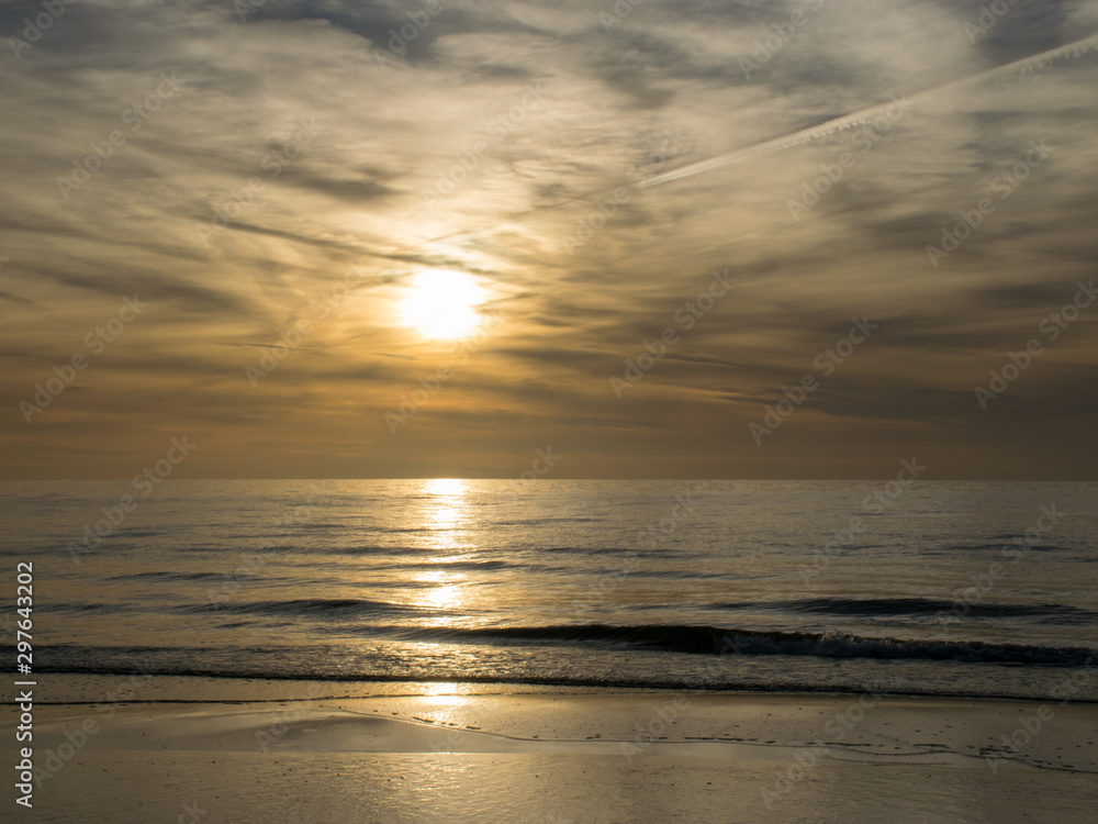 landscape with defocused beautiful dramatic golden sky over the sea, reflection at sunset time, long exposure 
