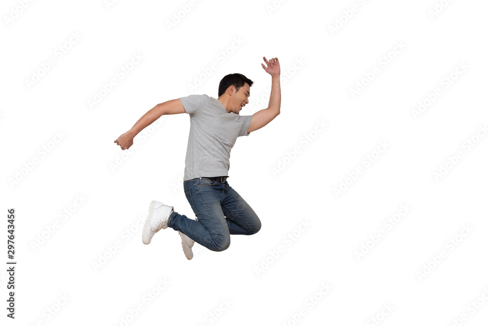 Full length portrait of an excited young Asian man in gray t-shirt jumping while celebrating success or dancing with music isolated over white background