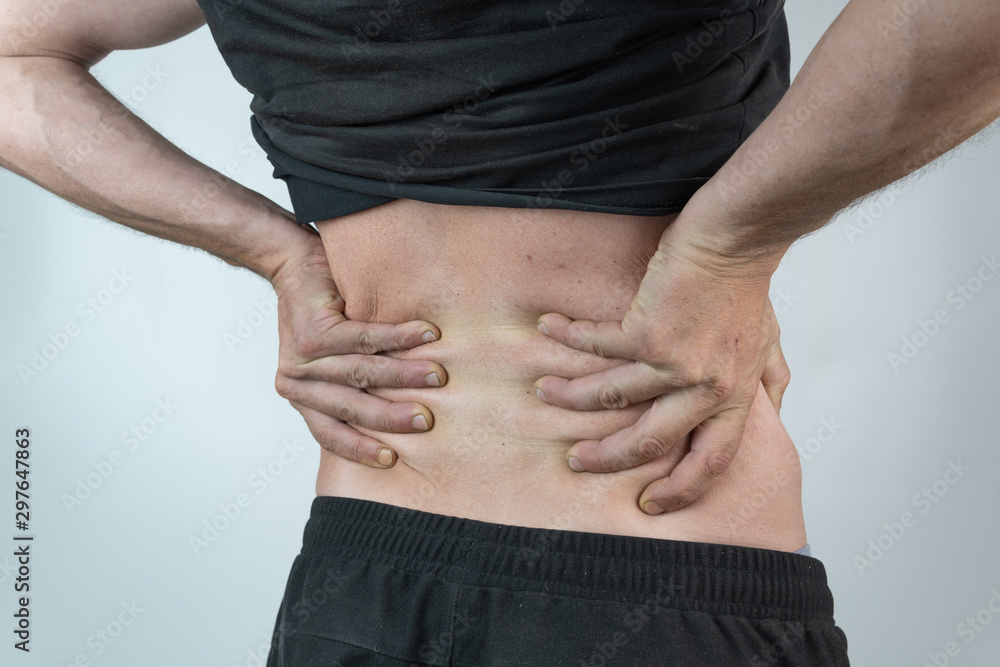 Naklejka premium back man dressed in black with his hands on his kidneys on isolated White background