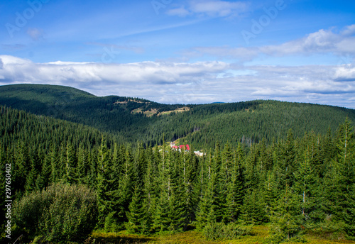 Mountain forest landscape with a red house far.
