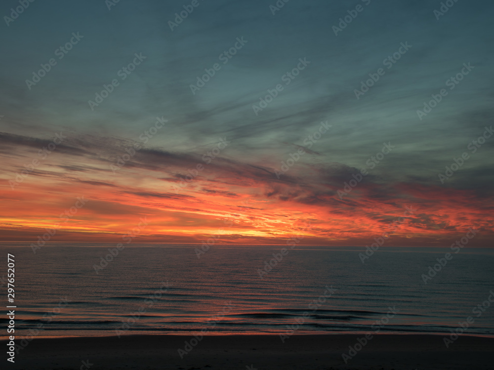 Fototapeta premium landscape with defocused beautiful dramatic golden sky over the sea, reflection at sunset time, long exposure 