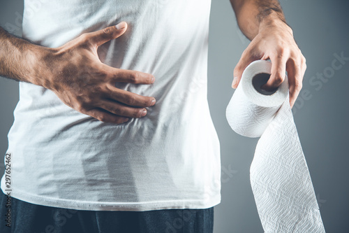 man holding a roll of toilet paper on gray background