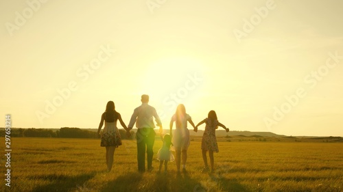 mother  father and little daughter with sisters walking in the field in sun. Happy young family. Children  dad and mom play in the meadow in the sunshine. The concept of a happy family.