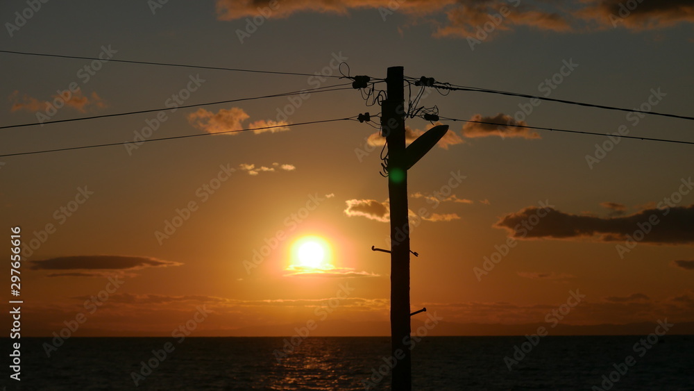 木製の電柱と夕日の海