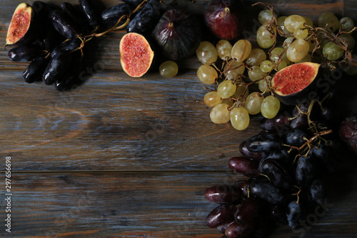Freshly picked autumn fruits. Black and white grapes and figs on dark wooden table
