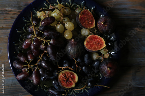 Freshly picked autumn fruits. Black and white grapes and figs on dark wooden table