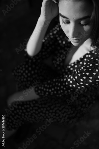 Beautiful girl in dress. Dress in polka dots. Girl on the street. Long and lush hair. Model appearance. Black and white photo. Retro photo