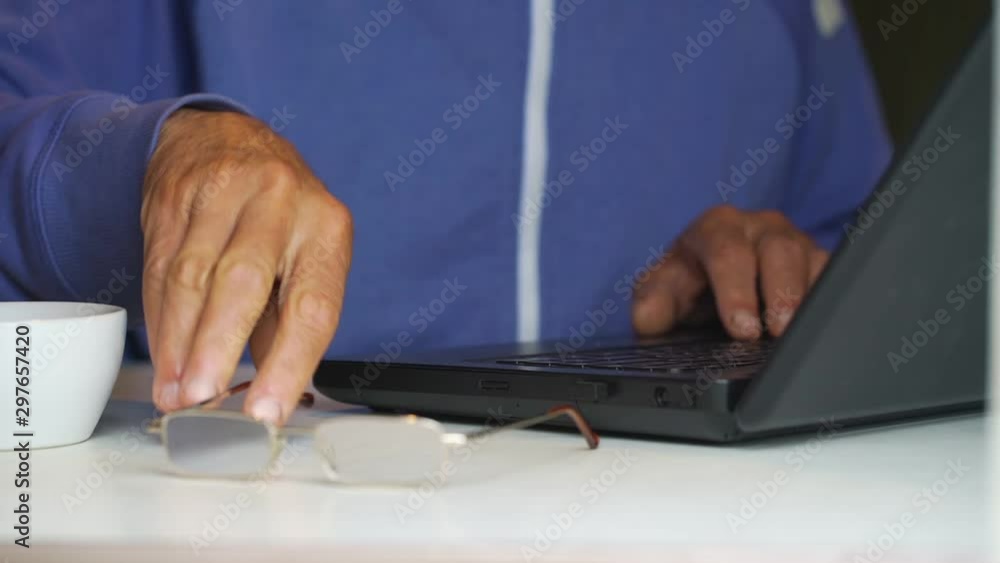 old man puts aside glasses in metal frame on table by teacup and continue working on laptop close view slow motion old man puts aside glasses in metal frame on table by teacup and continue working on laptop close view slow motion