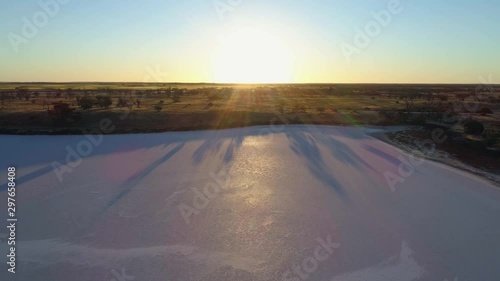 Forward flight descending over pink lake Hardy with sun flare at sunset photo