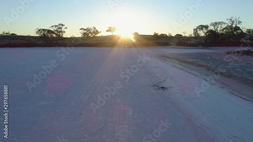 Backward flight low above salt lake surface facing the sun flare in Australia photo