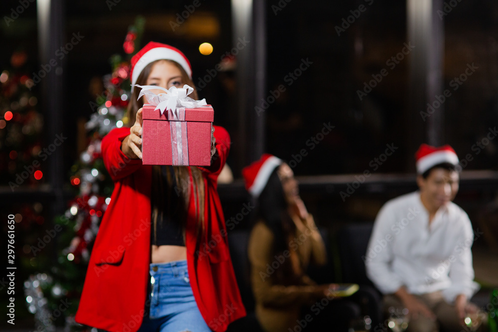 Caucasian beautiful girl holding gift boxes front of her colleagues having fun, Group of mix nationalities friends having Christmas party.