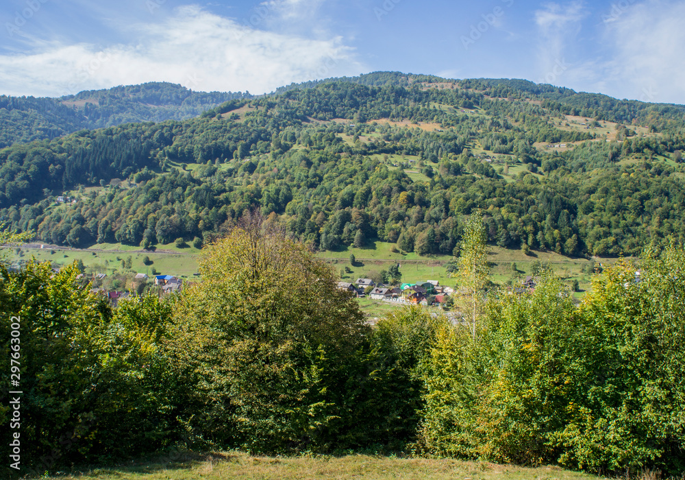 Mountain forest green landscape with houses and a far village.