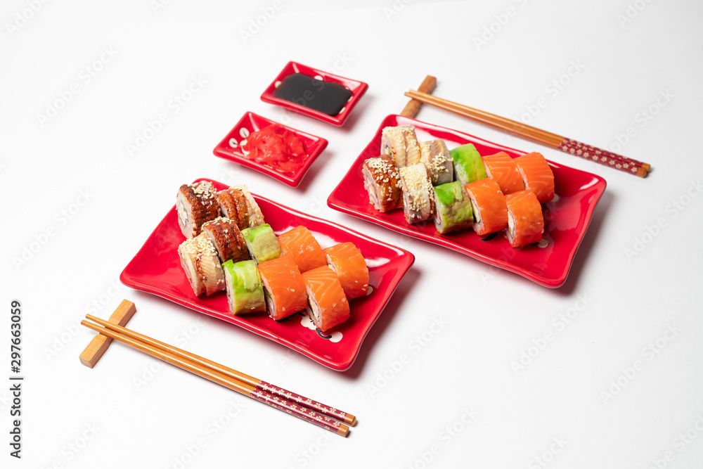 delicious sushi and rolls on a red plate on a white background. traditional Japanese cuisine delicious sushi and rolls on a red plate on a white background. traditional Japanese cuisine