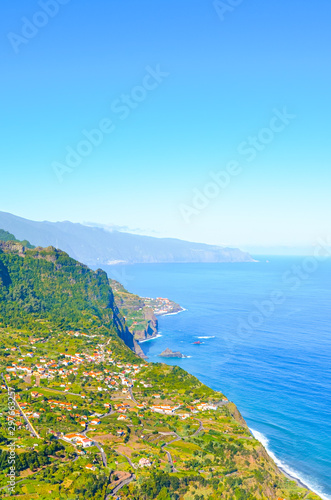 Amazing northern coast of the Portuguese Madeira island. Sao Jorge village surrounded by green hills and tropical forest  cliffs by the Atlantic ocean. View from the viewpoint on the top of the hill