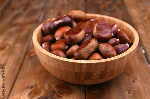 Cup of chestnuts on a wooden background. Autumn harvest and ripe fruits. Free space for text.
