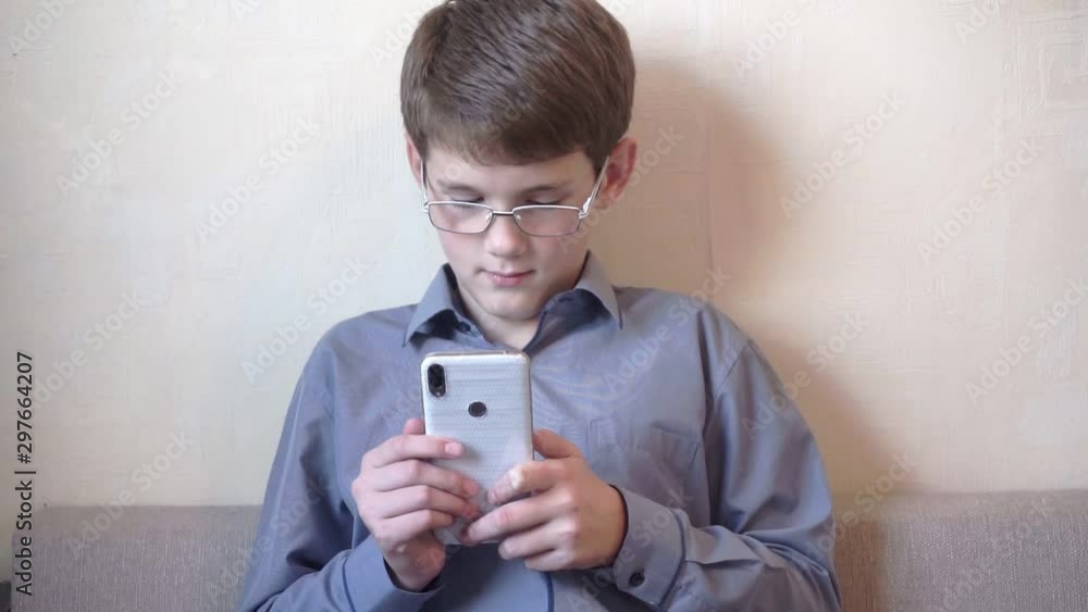 funny school-aged boy in glasses using a smartphone.portrait of a modern teenager. funny school-aged boy in glasses using a smartphone.portrait of a modern teenager.