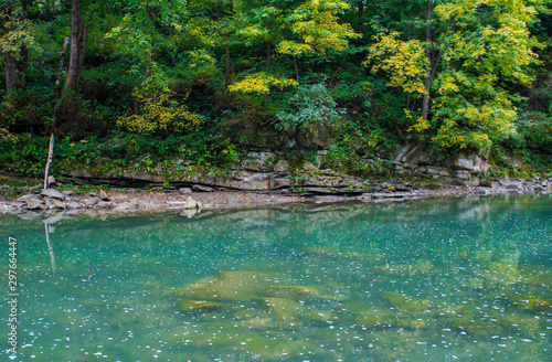 Beautiful turquoise blue mountain river. Large stones with rocks in the middle of a green forest.