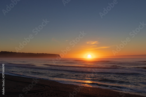 Sunset over forrest, waves and beach in New Zealand