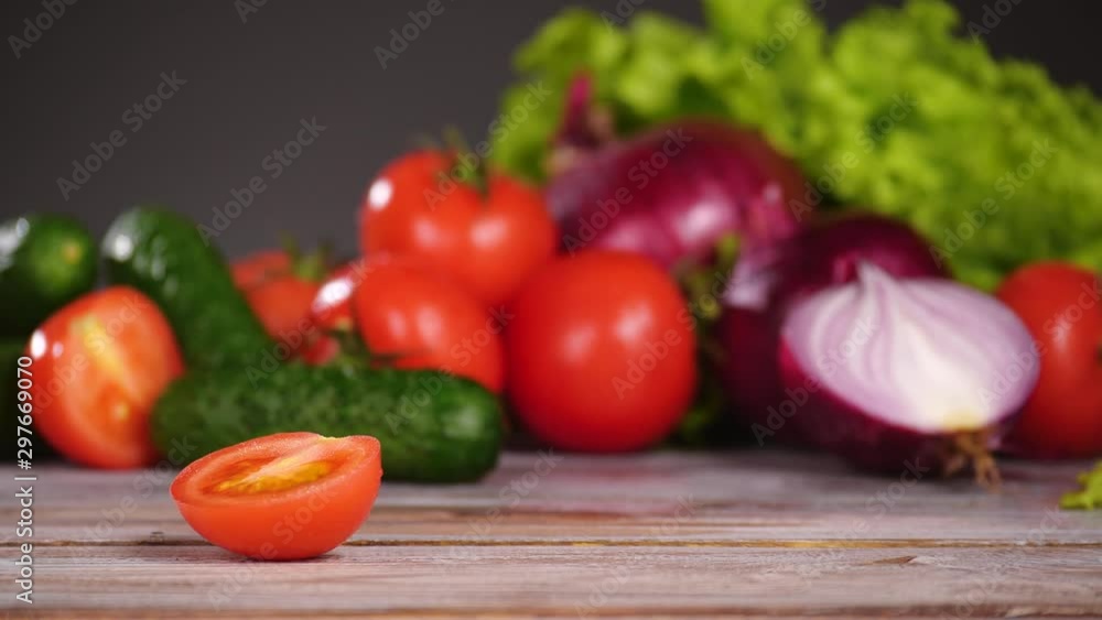Fresh vegetables on the wooden table. Hand takes half of tomato and slice it with a knife. Nobody in the frame. Fresh vegetables on the wooden table. Hand takes half of tomato and slice it with a knife. Nobody in the frame.