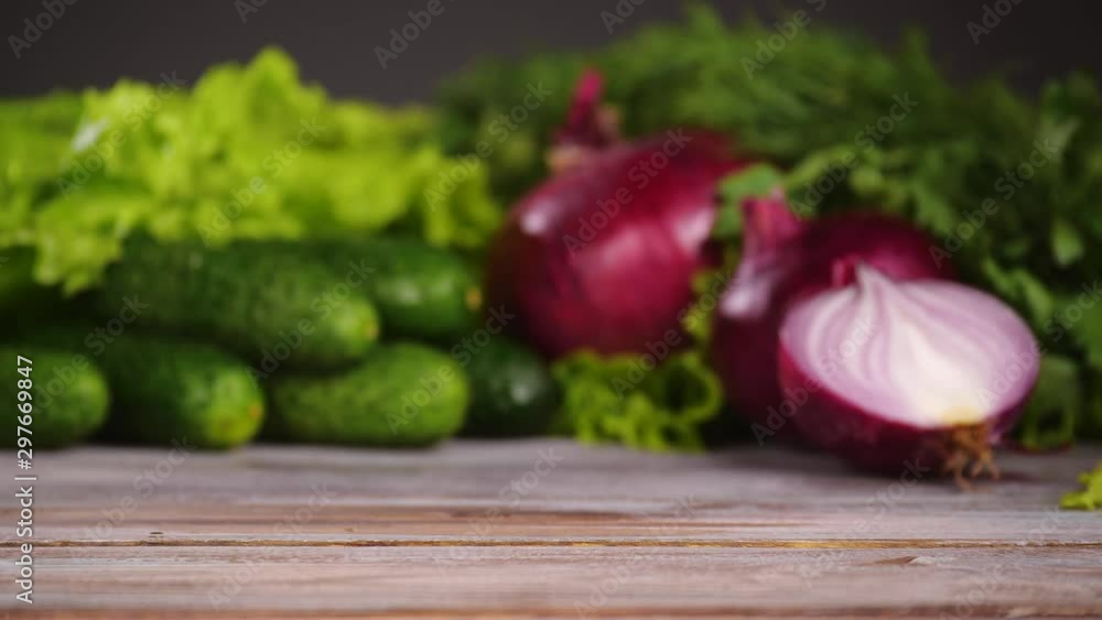 Fresh vegetables on the wooden table. Focus is sliding to foreground, hand puts cherry tomatoes on the table. Nobody in the frame. Fresh vegetables on the wooden table. Focus is sliding to foreground, hand puts cherry tomatoes on the table. Nobody in the frame.