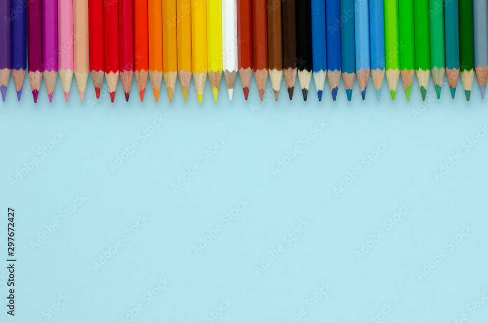 Fototapeta premium Colored pencils composition on blue background. Flat lay.