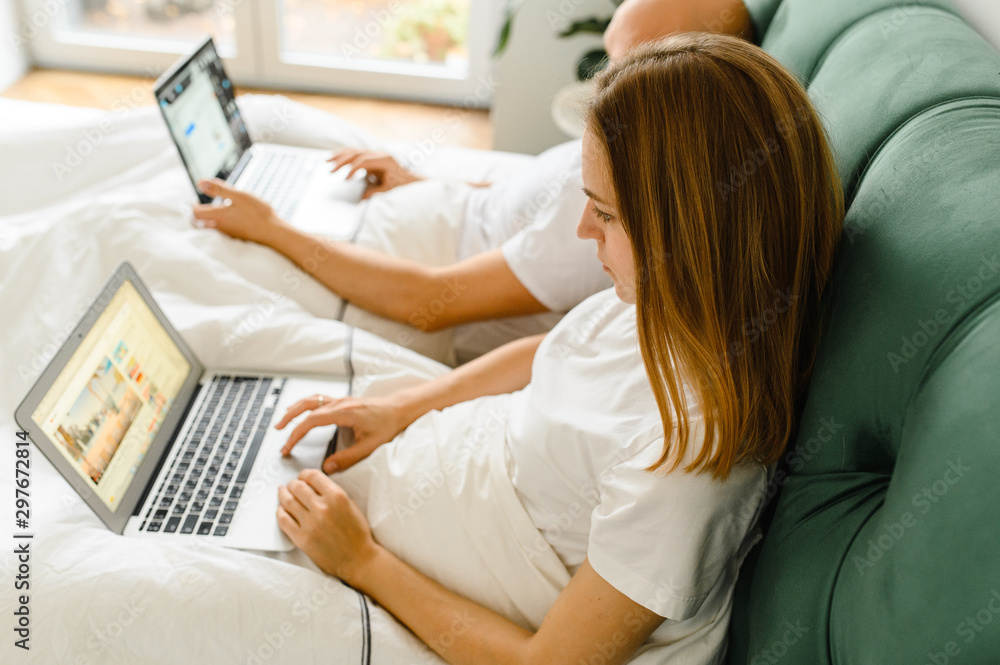 Obraz premium Young people at home or millennial beautiful couple in the hotel using internet connection and technology devices like computer laptop