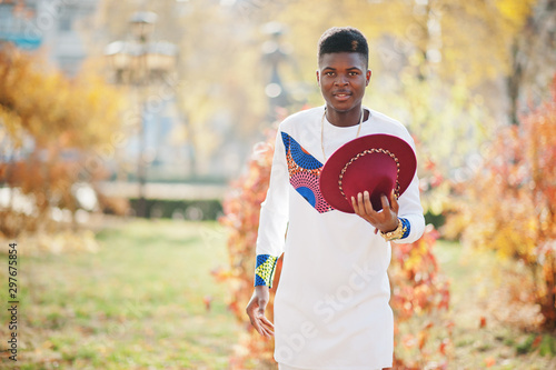 Stylish trendy afro france man in red hat and white outfit posed at autumn day. Black african model guy.