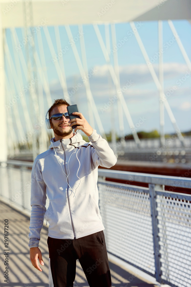 Portrait of young athlete man preparing to exercise using smart-phone on sunny day Portrait of young athlete man preparing to exercise using smart-phone on sunny day