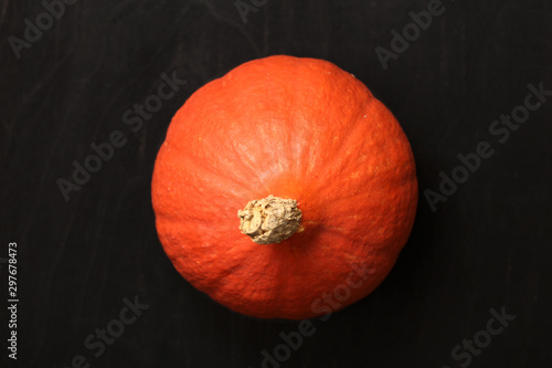 Raw red kuri squash on a dark background. Top view a small pumpkin without the ridges. photo