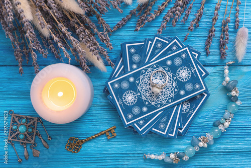 Blue tarot cards deck on blue wooden table flat lay background.