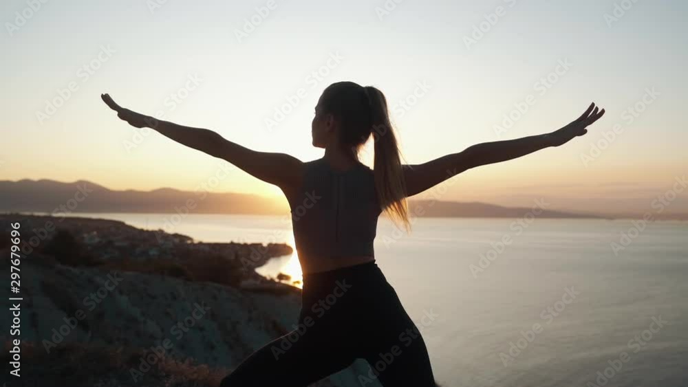 Silhouette of woman practices yoga and doing stretching at sunrise, slow motion Silhouette of woman practices yoga and doing stretching at sunrise, slow motion