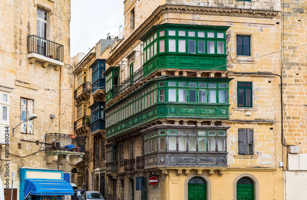 Fototapeta premium Residential house facade with traditional Maltese multicolored enclosed wooden balconies in Valletta, Malta, in summer day. Authentic Maltese urban scene.