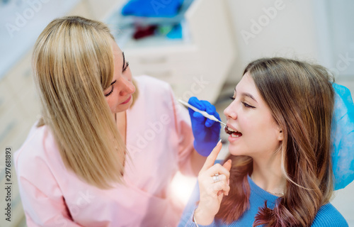 Attractive young woman in stomatology clinic with cheerful female dentist. Healthy teeth concept.