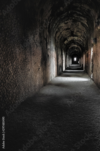 In the Ancient Temple of Jupiter in Terracina  Italy . Light paints the inner concrete ceiling. A white figure looks outside at the end of the corridor.