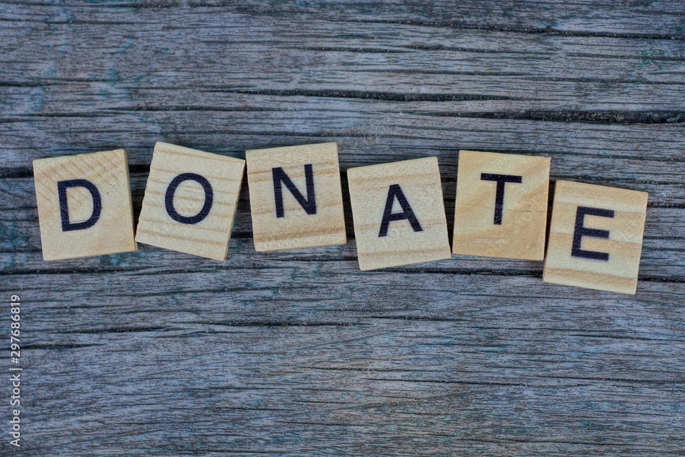Fototapeta premium word donate made of wooden letters on a gray table