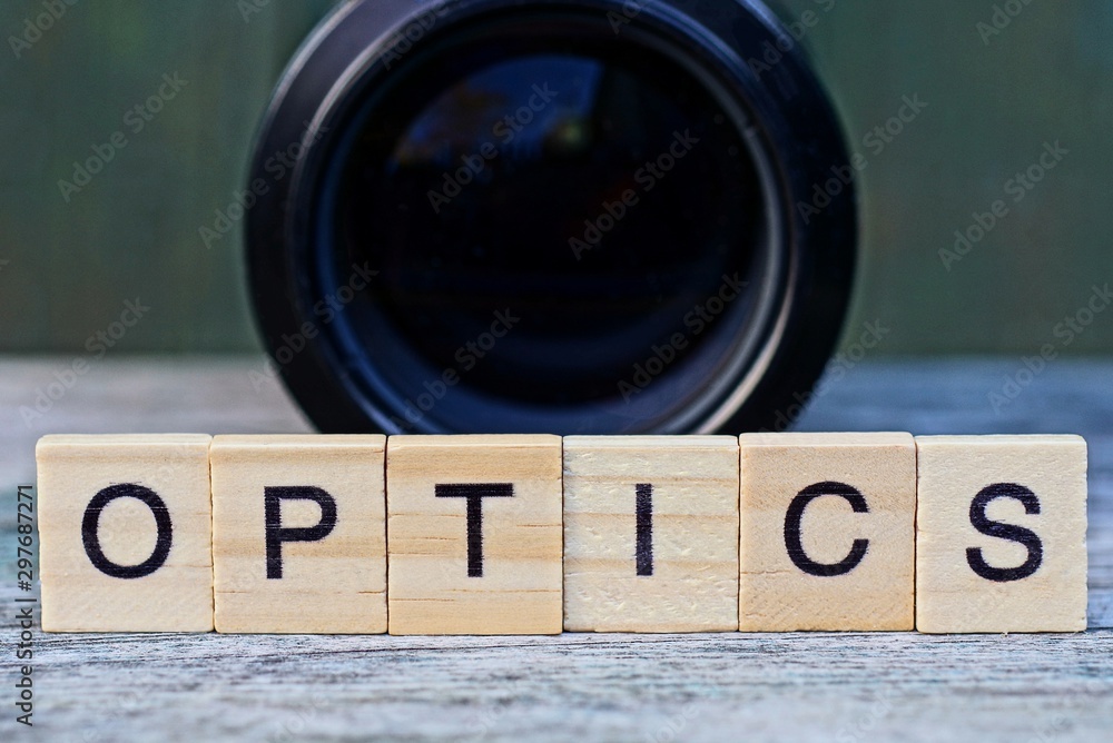 word optics made of wooden letters and black lens on a gray table