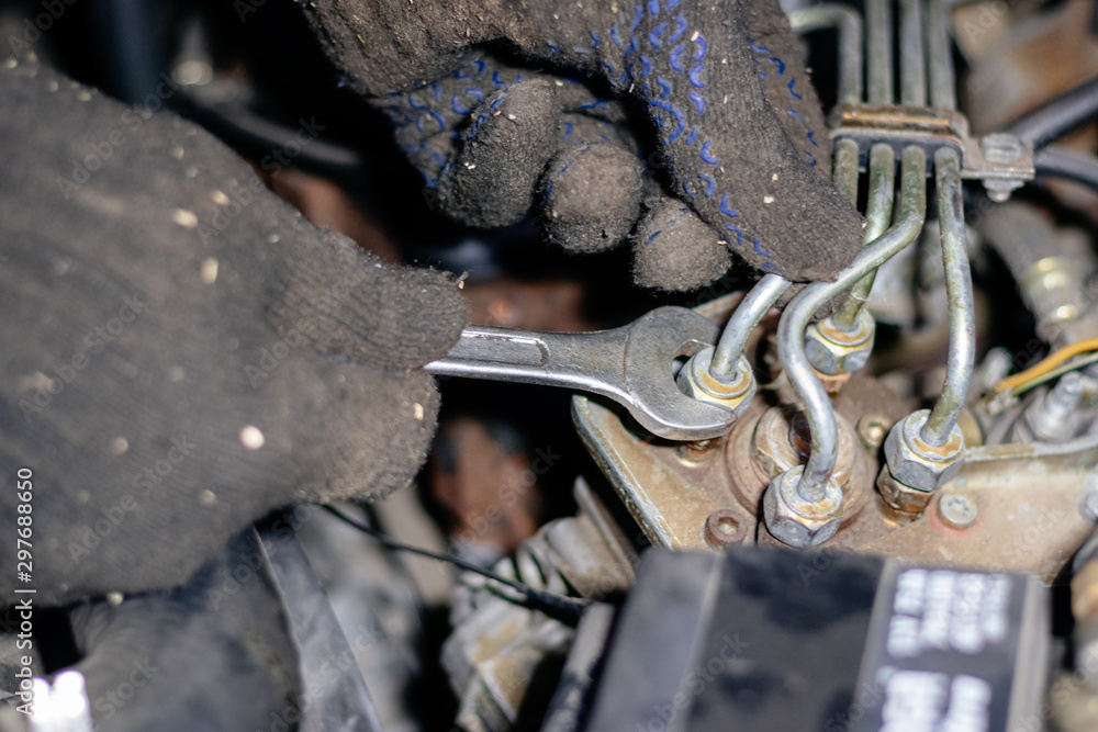 Man mechanic works in the garage. Repairs the engine of an old car Man mechanic works in the garage. Repairs the engine of an old car
