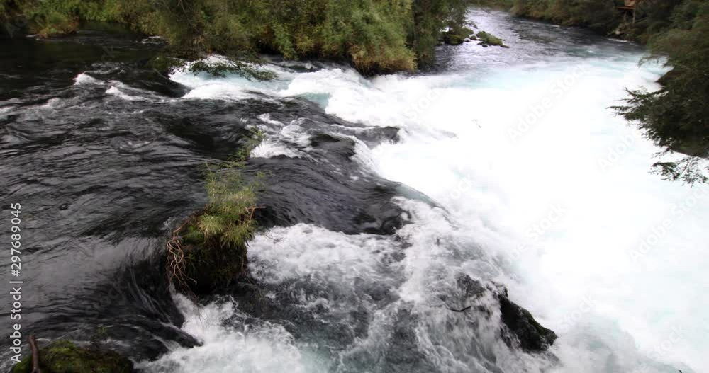 The wild white waters of Caburgua River flowing down and jumping at Carileufu waterfall. An amazing scenery inside the south of Chile rainforest at Pucon, an idyllic landscape for some relax time The wild white waters of Caburgua River flowing down and jumping at Carileufu waterfall. An amazing scenery inside the south of Chile rainforest at Pucon, an idyllic landscape for some relax time